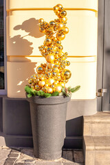 Artificial Christmas tree made entirely of golden baubles in pot. Funny xmas from shiny gold balls in flowerpot
