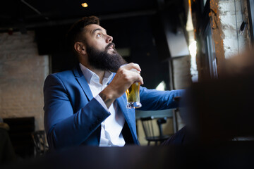 Worried man looking at the sky fearfully holding a glass of beer
