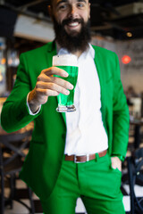 Bearded man dressed in green for St. Patrick's Day holding a beer