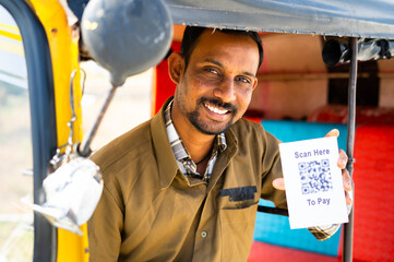 Smiling auto driver showing qr or barcode scanner for contectless e-payment by looking at camera - concept of cashless digital payment recommendation.