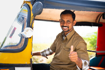 Auto rickshaw driver showing thumbs up while on auto - concept of approval to ride or travel, occupation and self employed - obrazy, fototapety, plakaty