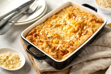 Pudding or oatmeal pie in a baking dish on a light gray culinary background. Casserole of cereals with nuts on the kitchen table closeup. Healthy and nutritious breakfast