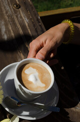 cup of coffee with milk in woman's hand