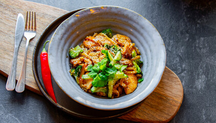 A bowl of udon with chicken and broccoli