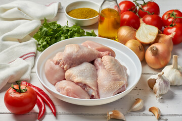 raw chicken pieces tomatoes onions garlic chili pepper fresh coriander dill parsley on white background