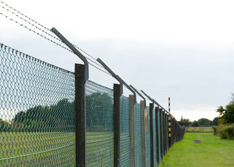 Barbed wire fence protecting a border from illegal trespassing from refugees, migrants and illegal...