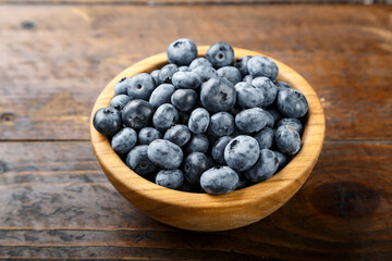 Blueberry berries are in a wooden plate on wooden background. Healthy food and healthy lifestyle.