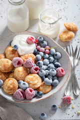 Homemade mini pancakes with yoghurt and frozen berries.