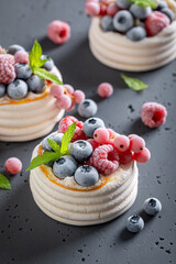 Creamy mini Pavlova dessert with whipped cream and frozen fruit.