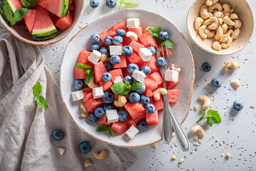 Tasty watermelon salad with cashews, blueberries and mint leaves.