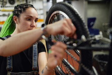 Serious female master checking wheel of bicycle