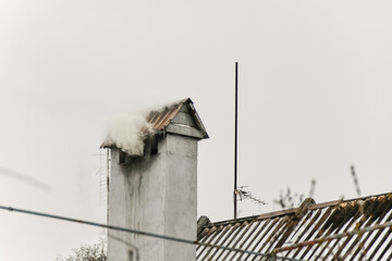 Heating a private house during the cold season with the help of firewood. Thick white smoke comes from the chimney.