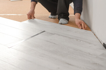 Unrecognizable man laying laminate flooring. Repair in the apartment. Professional laying of a...
