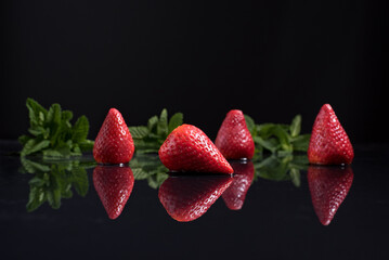 Fresas enteras con hojas de menta aisladas. Reflejo espejo sobre agua y fondo negro  © R. Guas