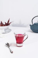 Obraz na płótnie Canvas Una taza transparente de té de bayas con tetera de hierro azul sobre una mesa blanca y un fondo gris claro 