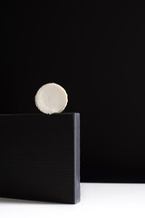 Queso cremoso de cabra sobre piedra negra y fondo negro. Concepto minimalista	