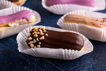 Beautiful delicious French eclairs with custard, covered with multi-colored icing.
