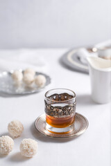 Un vaso de té clásico con dulces chocolates blancos cubiertos de coco en el cuadro blanco	