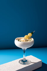 Crema de almendras, sopa española fría. Ajo blanco malagueño con almendras y uvas servido en un vaso sobre fondo azul	