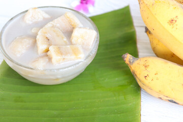 Banana in coconut milk. Traditional Asian dessert. Fruit dessert. With copy space on the wooden table.