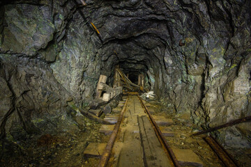 Fototapeta na wymiar Underground gold mine tunnel with wooden timbering and rails