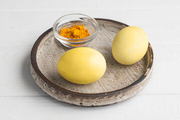 Concept of natural dye for Easter eggs. Coloring Easter eggs yellow color with turmeric.