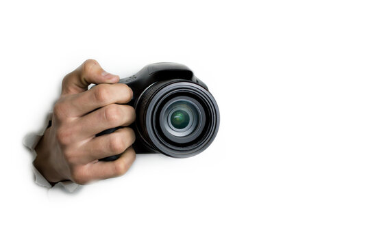 The concept of paparazzi or hidden camera, a hand holds a photo camera on a white background.