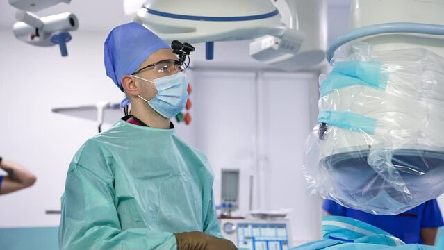 Confident middle-aged surgeon does laparoscopic operation in modern hospital. Portrait of a male doctor focused on work.