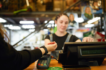 Female customer paying with smart watch via terminal