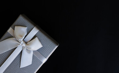 Big day gift, grey gift box with luxury bow on dark background with copy space.