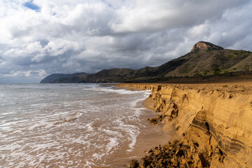 golden brown sandy beach landscape with mountain landscape behind under an expressive sky