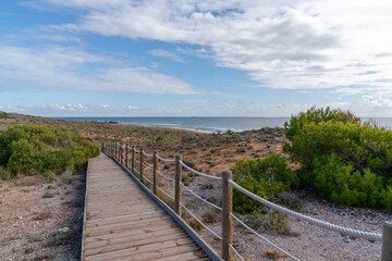 Fototapeta na wymiar long wooden boardwalk leads to a secluded and idyllic beach on the Mediterranean Sea