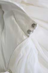Detail of a wedding dress made of satin. A full cut skirt, a belt with a zipper drape and hooks. A delicate cream shade. Concept: wedding celebration, evening dress salon, luxury atelier, fabric store