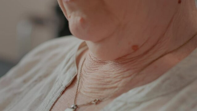 Elder woman with wrinkled and loose skin on neck. Senior person with natural wrinkles wearing necklace with jewellery, enjoying retirement. Aging person with gold bijouterie. Close up