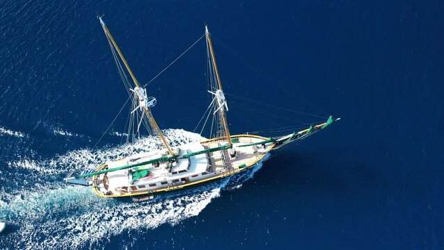 Aerial drone video of beautiful wooden deck classic sailing yacht cruising in open ocean deep blue sea