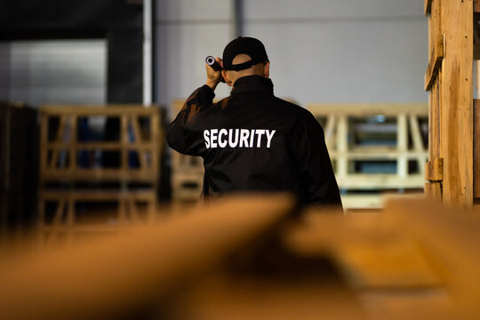 Security Guard Walking Building Perimeter With Flashlight