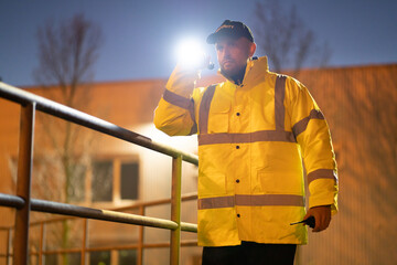 Security Guard Walking Building Perimeter With Flashlight