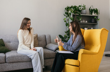 a satisfied female patient is sitting on the couch at a psychologist's appointment. Successful course of psychotherapy