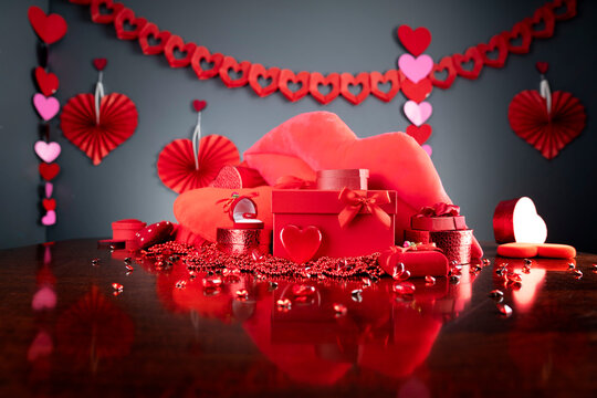 
Valentines day concept. Red hearts,  boxes with valentines gifts and valentines decorations on the glass table.

