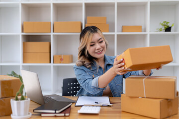 Asian woman checking parcel boxes for customers, she owns an online store, she takes orders from customers on the website and sends them through a private courier service. Online selling concept.