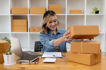 Asian woman checking parcel boxes for customers, she owns an online store, she takes orders from customers on the website and sends them through a private courier service. Online selling concept.