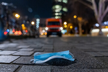 Mund Nasen Schutz bzw Maske auf der Straße Abends mit Bokeh