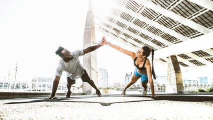 Athletic couple doing fitness exercise on city street - Man and woman training outdoor staying in...