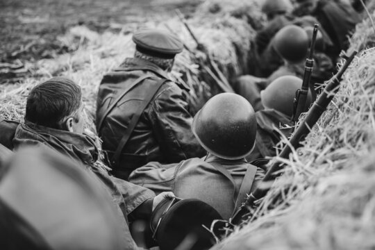 Re-enactors Dressed As World War II Russian Soviet Red Army Soldiers Hidden Sitting In Trench. Photo In Black And White Colors. WWII WW2.