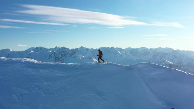 Young man climbing on ski in Alps. Aerial footage of winter activity. Alpin hiking, beautiful snowy mountain peaks.