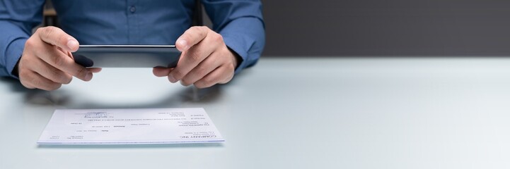 Man Taking Photo Of Cheque To Make Remote Deposit