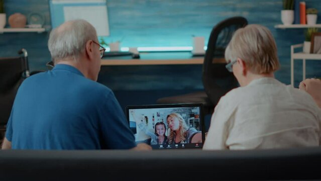 Elder couple using online teleconference to chat with relatives on laptop computer. Senior people talking to daughter and little child on videoconference call for remote communication.