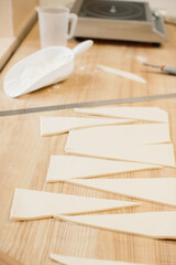 Woman baker cuts the dough into triangles for croissants. Making croissants in the bakery.