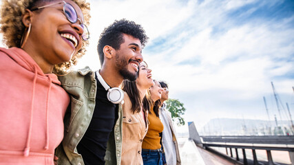 Diverse young friends hugging each other outdoors - Multiethnic group of people  standing together showing unity and teamwork - Support and community concept - obrazy, fototapety, plakaty