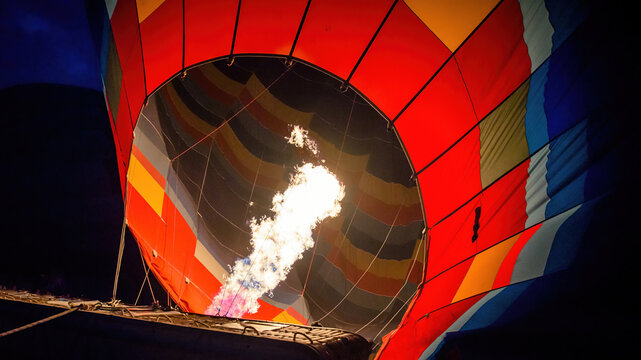 A hot air balloon being hot air filled with flames before sunrise. Close up of burner flame during balloon glow at night in Goreme, Cappadocia, Turkey